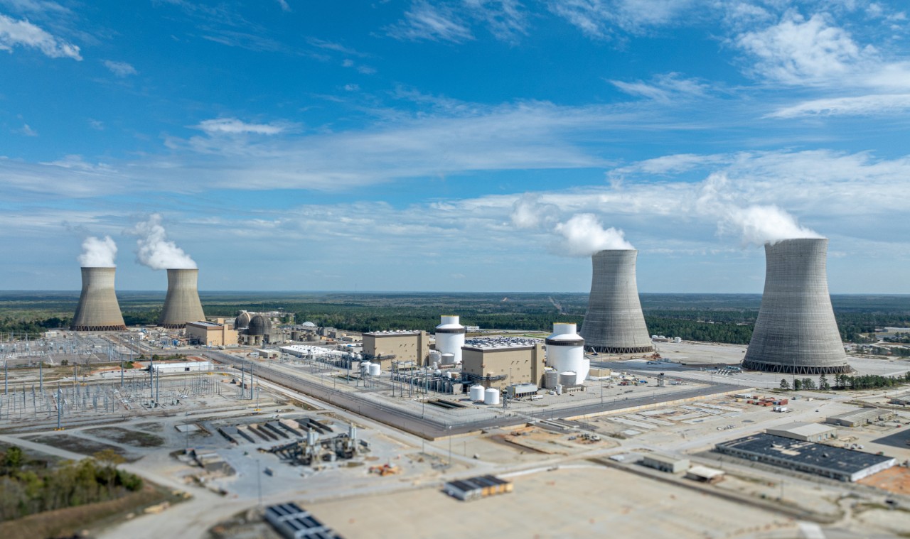 A wide aerial of Plant Vogtle shows cooling towers and units, illustrating large-scale nuclear development and carbon-free energy transition.