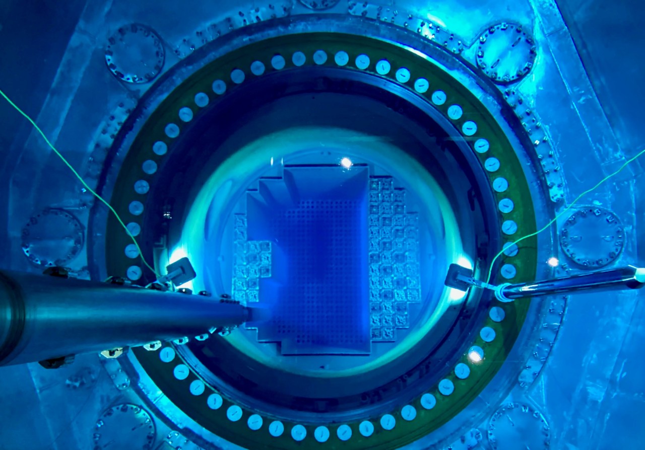 Looking down into a reactor vessel submerged in glowing blue water, capturing the heart of nuclear energy innovation in clean power production.