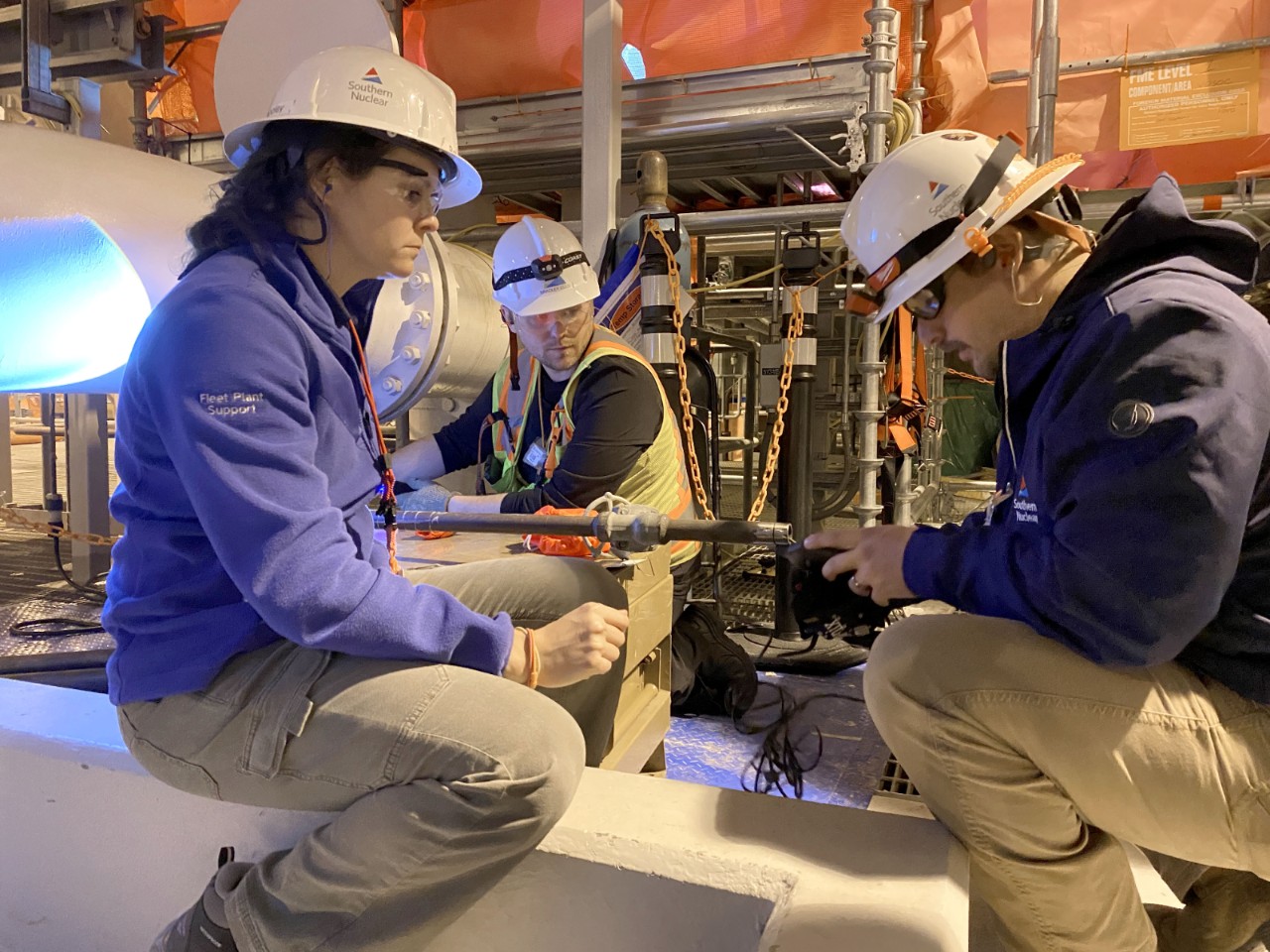 Engineers wearing Southern Nuclear hard hats collaborate inside a plant, advancing nuclear energy innovation through system upgrades.